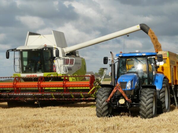 blue tractor next to white farm vehicle at daytime