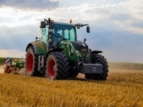 green tractor plowing the fields on focus photography