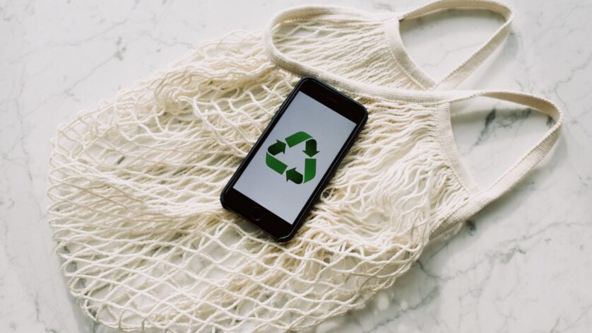 mobile phone with green recycling sign and mesh bag