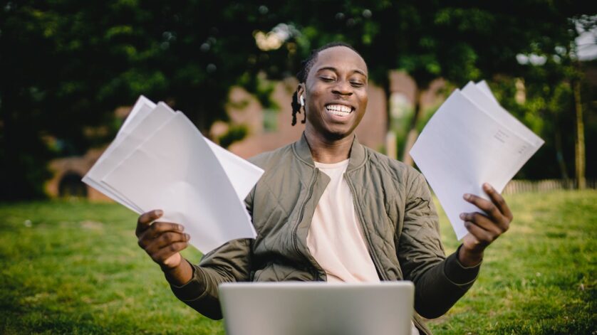 student with documents and laptop happy about getting into university