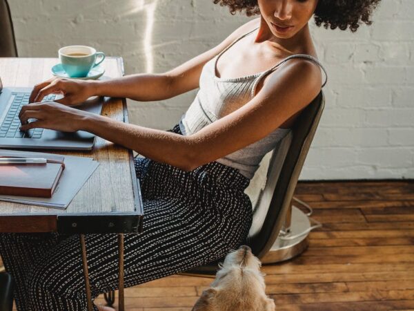 african american woman working on computer with dog near