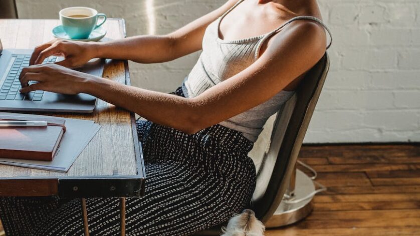 african american woman working on computer with dog near