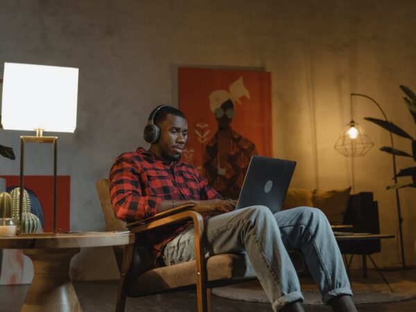 man sitting on an armchair while using his laptop