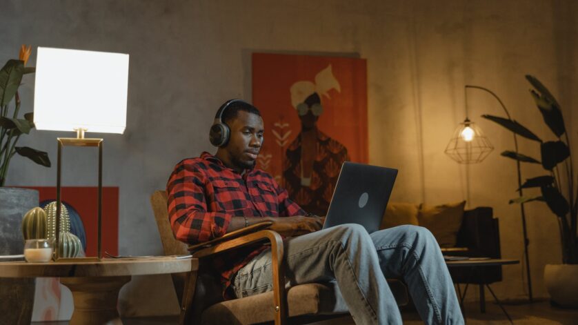 man sitting on an armchair while using his laptop