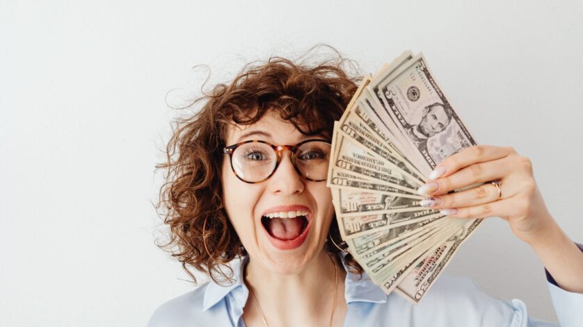 happy woman in blue long sleeve blouse holding money